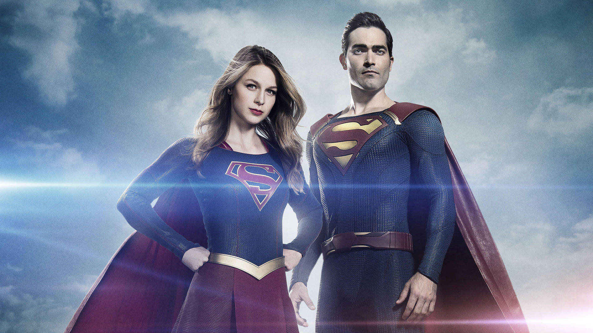 Supergirl 和 Superman 穿著超級英雄服裝，在多雲的天空下英勇地站立，帶有鏡頭光暈。
