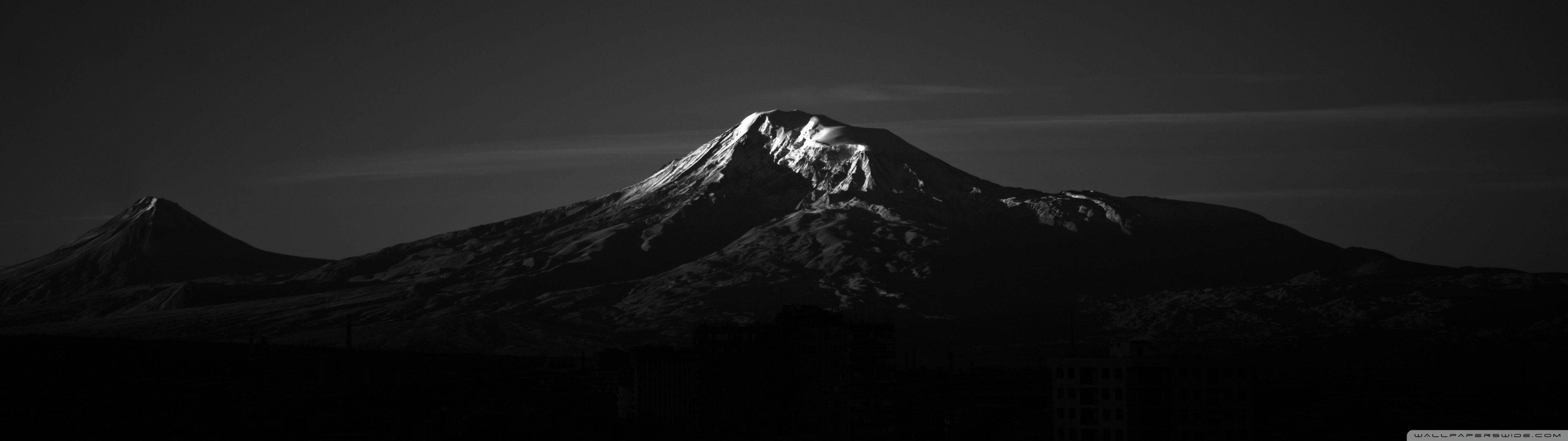 白雪覆蓋的山峰在昏暗的天空和隱約的雲層中形成剪影。