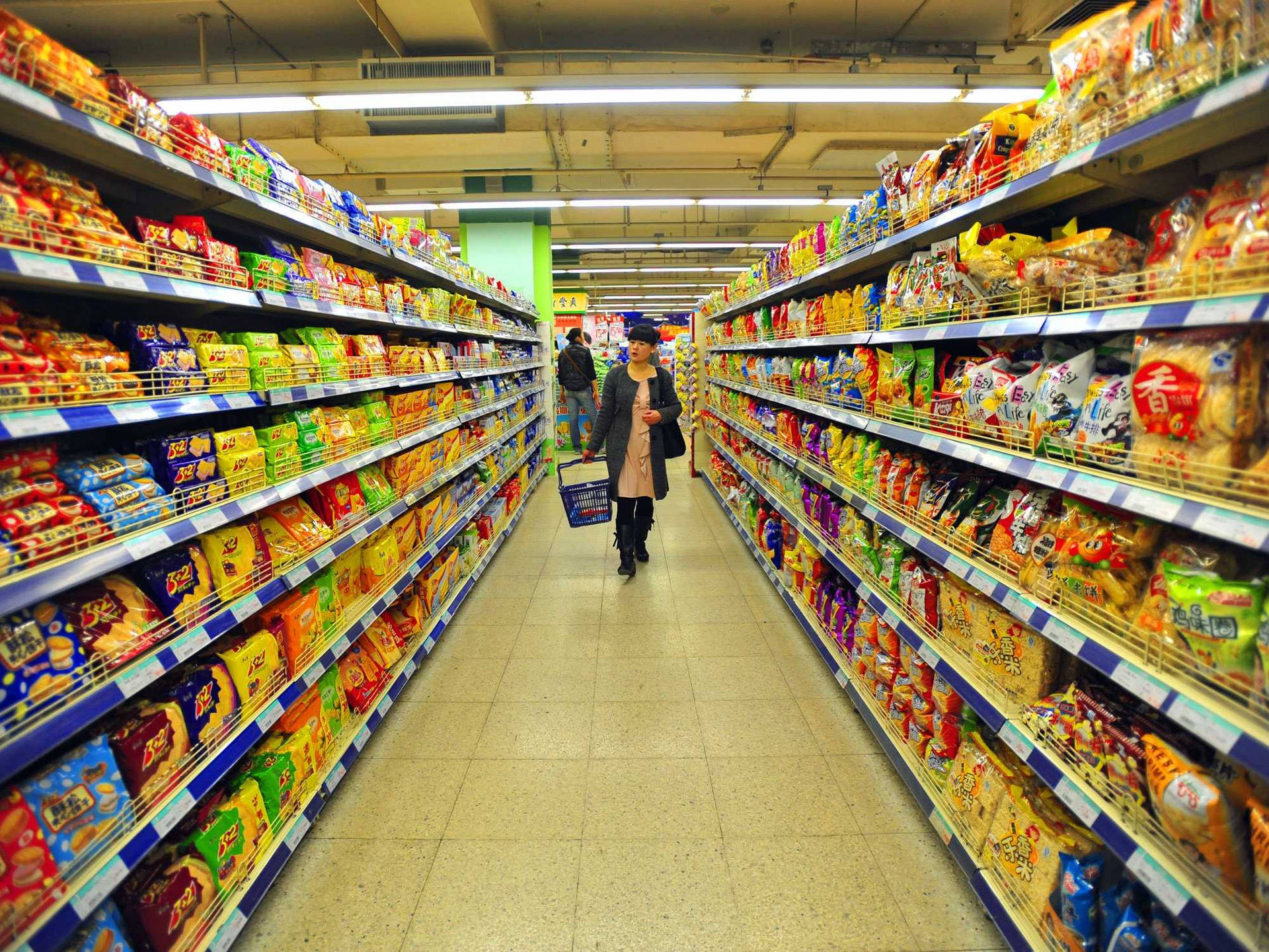 在擺滿零食產品的超市通道中購物的人。