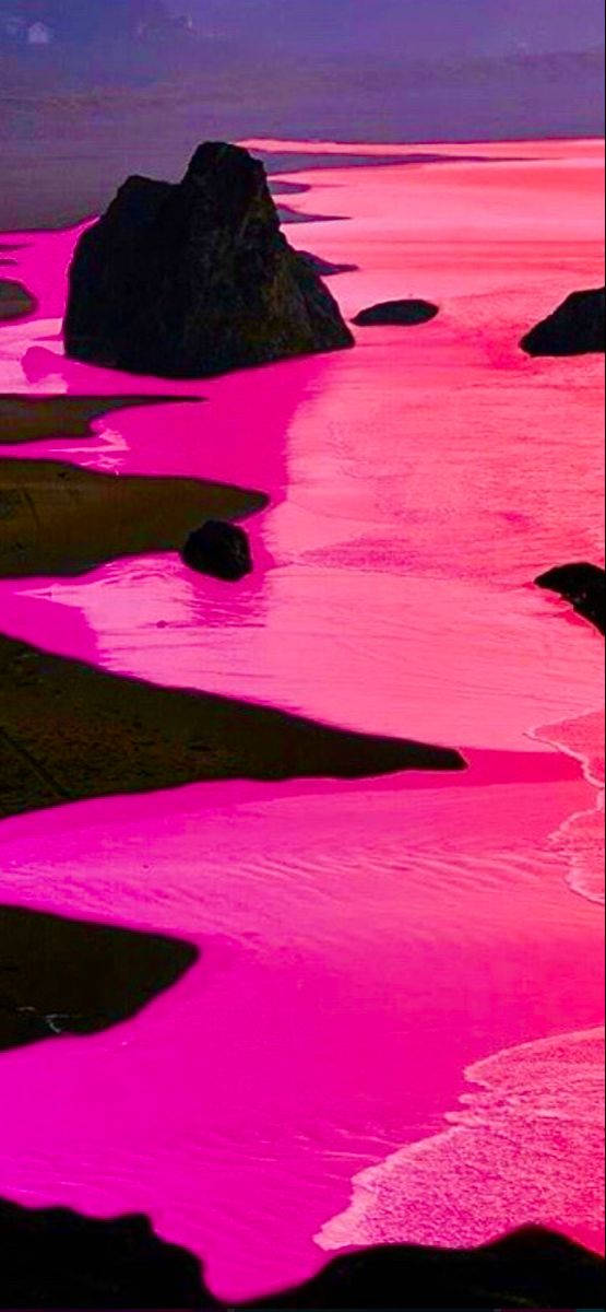 Hot Pink Aesthetic 桌布 壁紙 — 超現實的海岸場景，在紫色天空下，鮮豔的粉紅色水流繞過深色岩石。