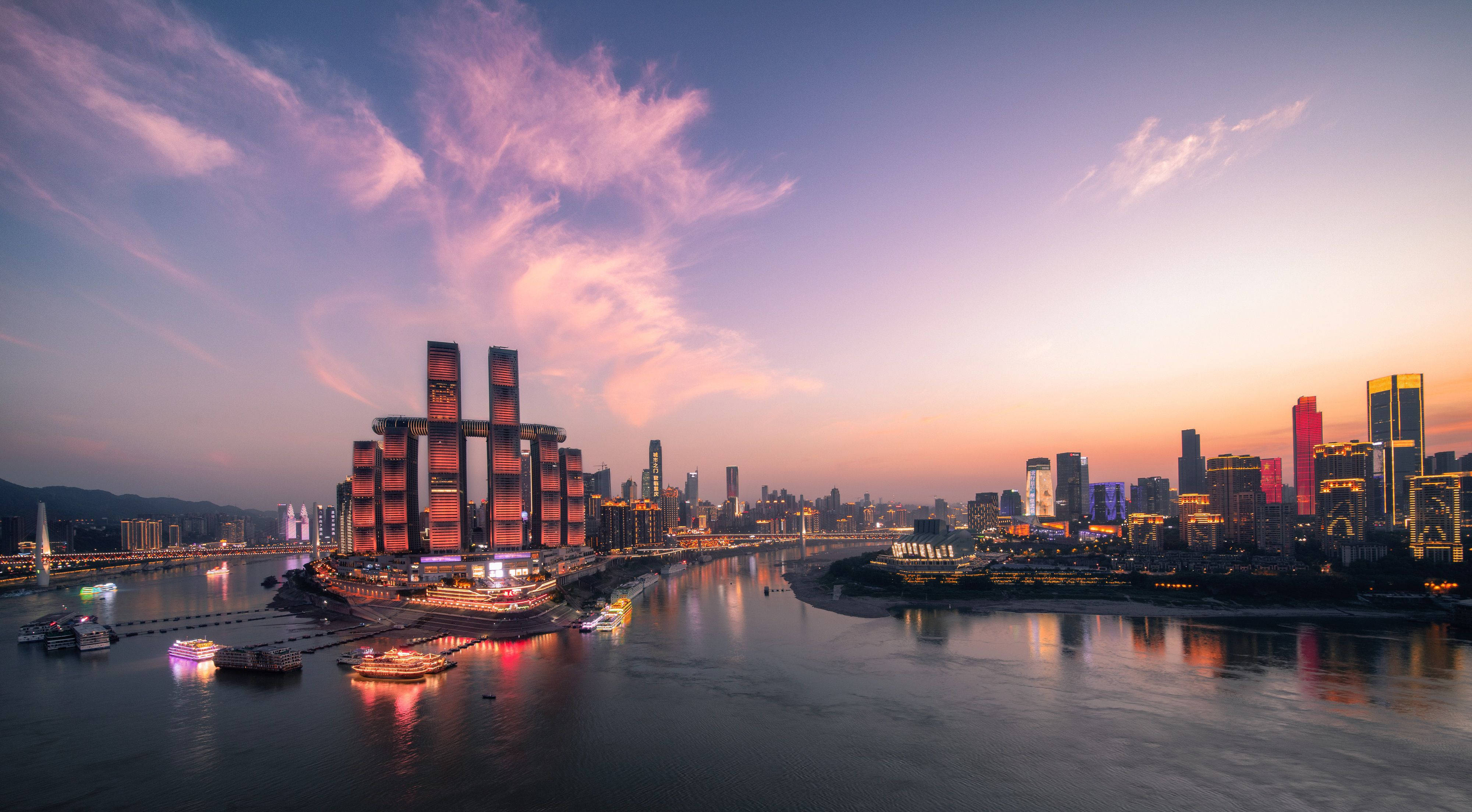 超級城市重慶中國城市風景 壁紙 — 在粉紅色和紫色雲彩下，夕陽時分充滿活力的城市天際線，閃爍的摩天大樓和反射河流上的船隻。