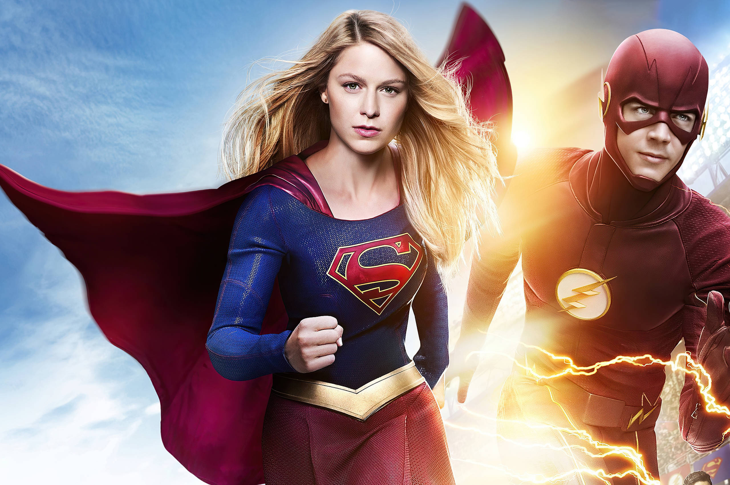 超級女孩與閃電俠 壁紙 — Supergirl 和 The Flash 英雄般地站在明亮的天空下，閃電在他們周圍劈啪作響。