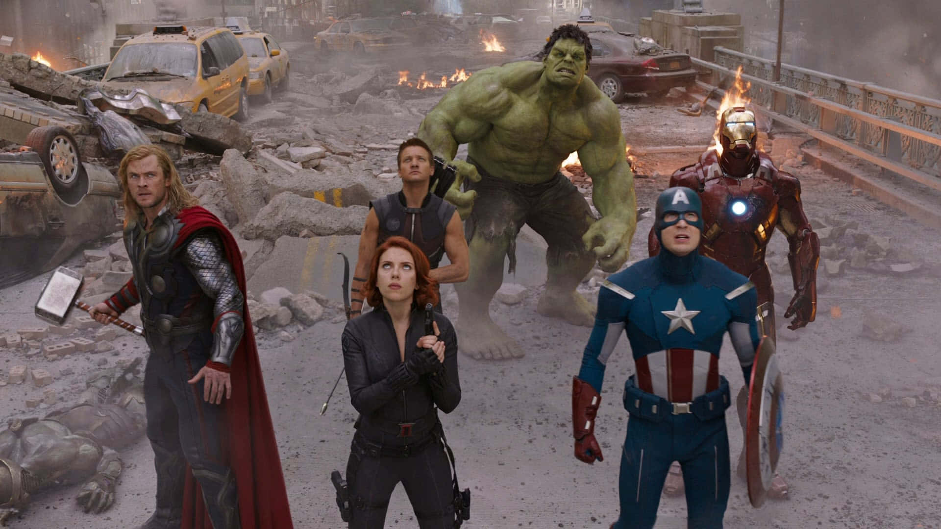 New Avengers 桌布 壁紙 — 超級英雄在煙霧瀰漫的天空下，站在一條被戰爭摧毀的街道上，周圍是燃燒的汽車和瓦礫。