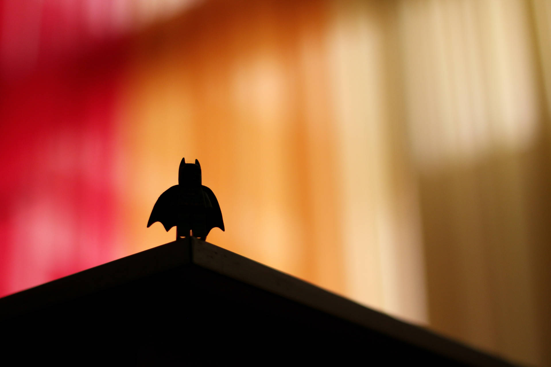 LEGO Batman 人物剪影在屋頂上，背景溫暖發光。