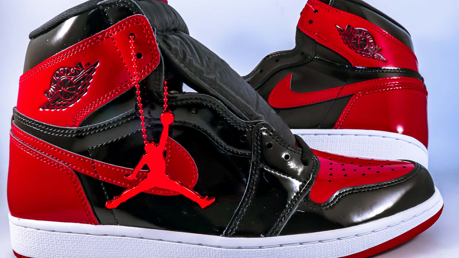 閃亮的黑色和紅色 Jordan 1 運動鞋，鞋帶上掛著 Jumpman 標誌。