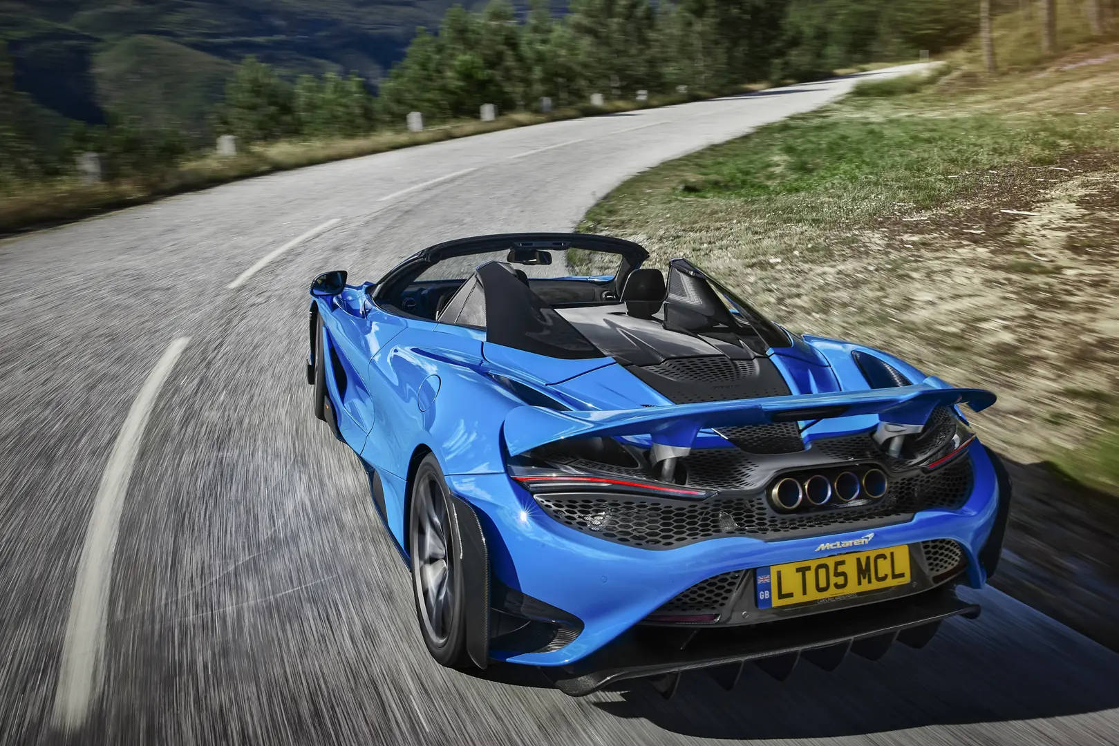藍色McLaren 570S Spider在日落時分於山路上疾馳。