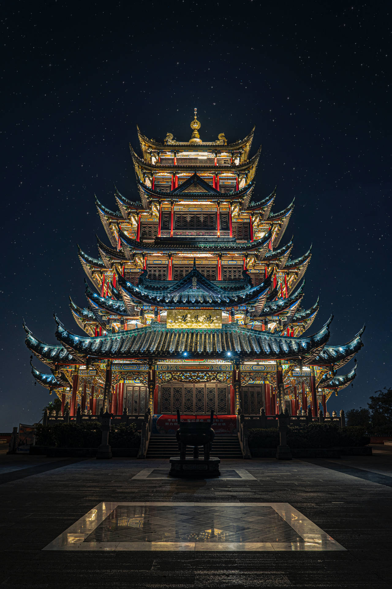 星空下被照亮的傳統寶塔，前景有倒影池
