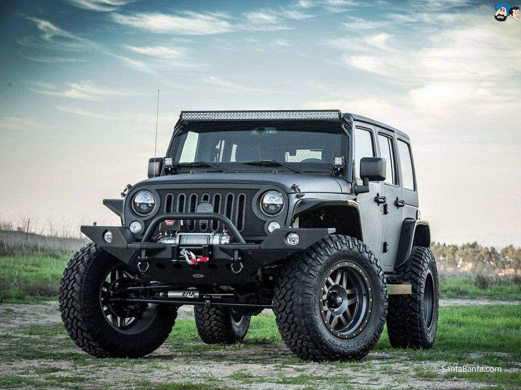日落時停放在草地上的黑色改裝Jeep Wrangler