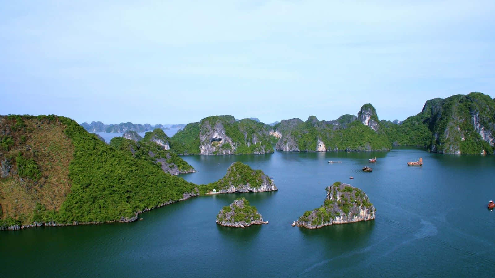 鬱鬱蔥蔥的喀斯特島嶼從平靜的藍色海水中升起，天空晴朗。