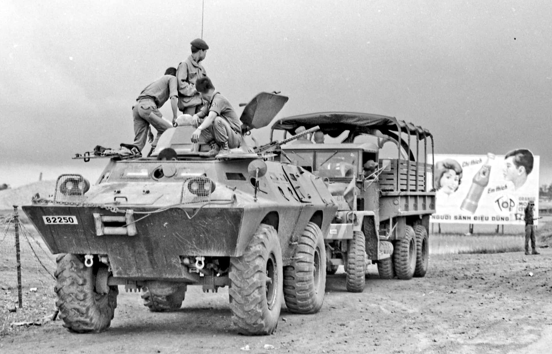 士兵在裝甲車上，旁邊是帶廣告牌的卡車。