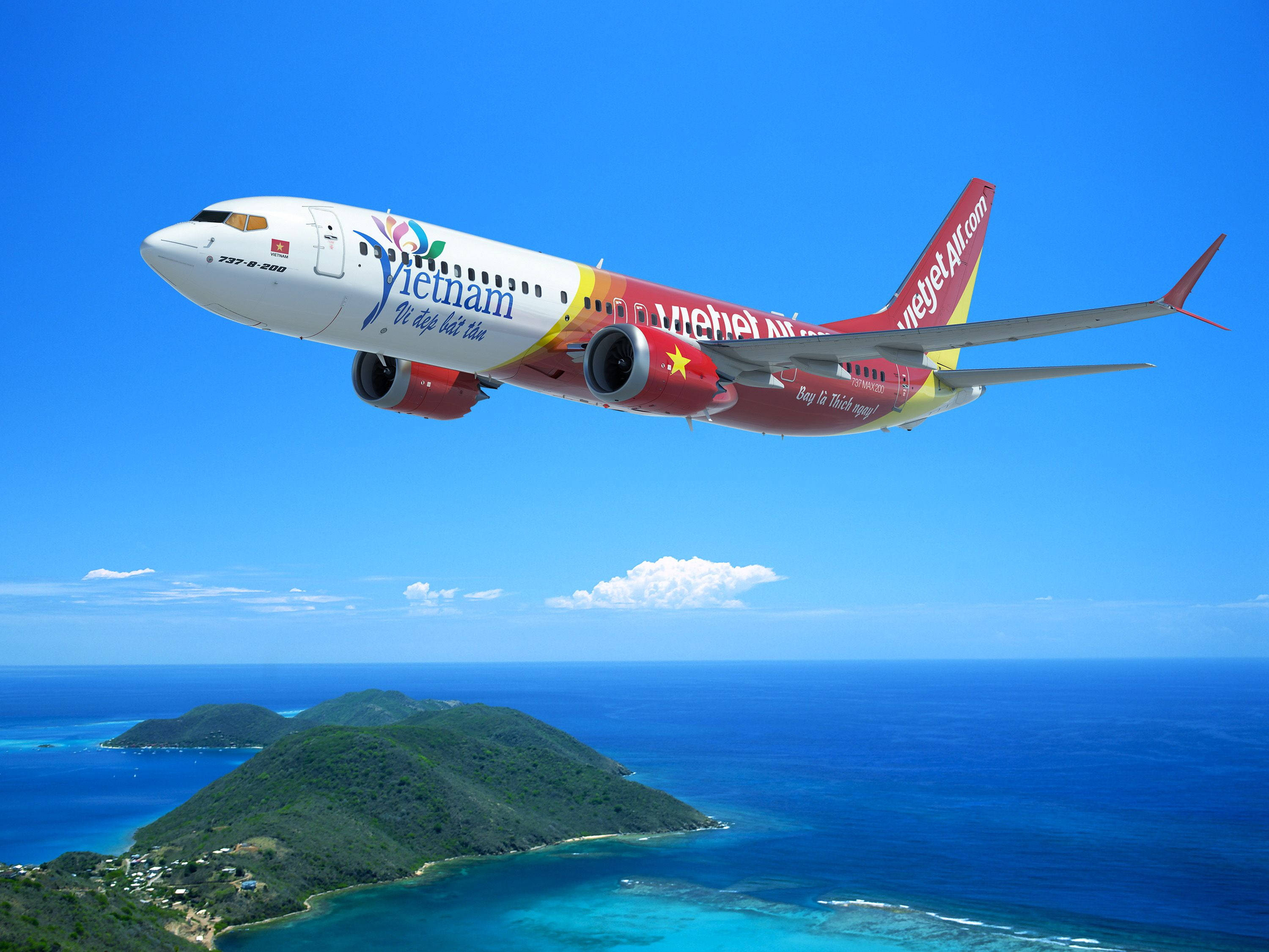 島嶼 桌布 壁紙 — 越南航空噴射機在清澈藍天下翱翔於碧綠海水和翠綠島嶼之上。
