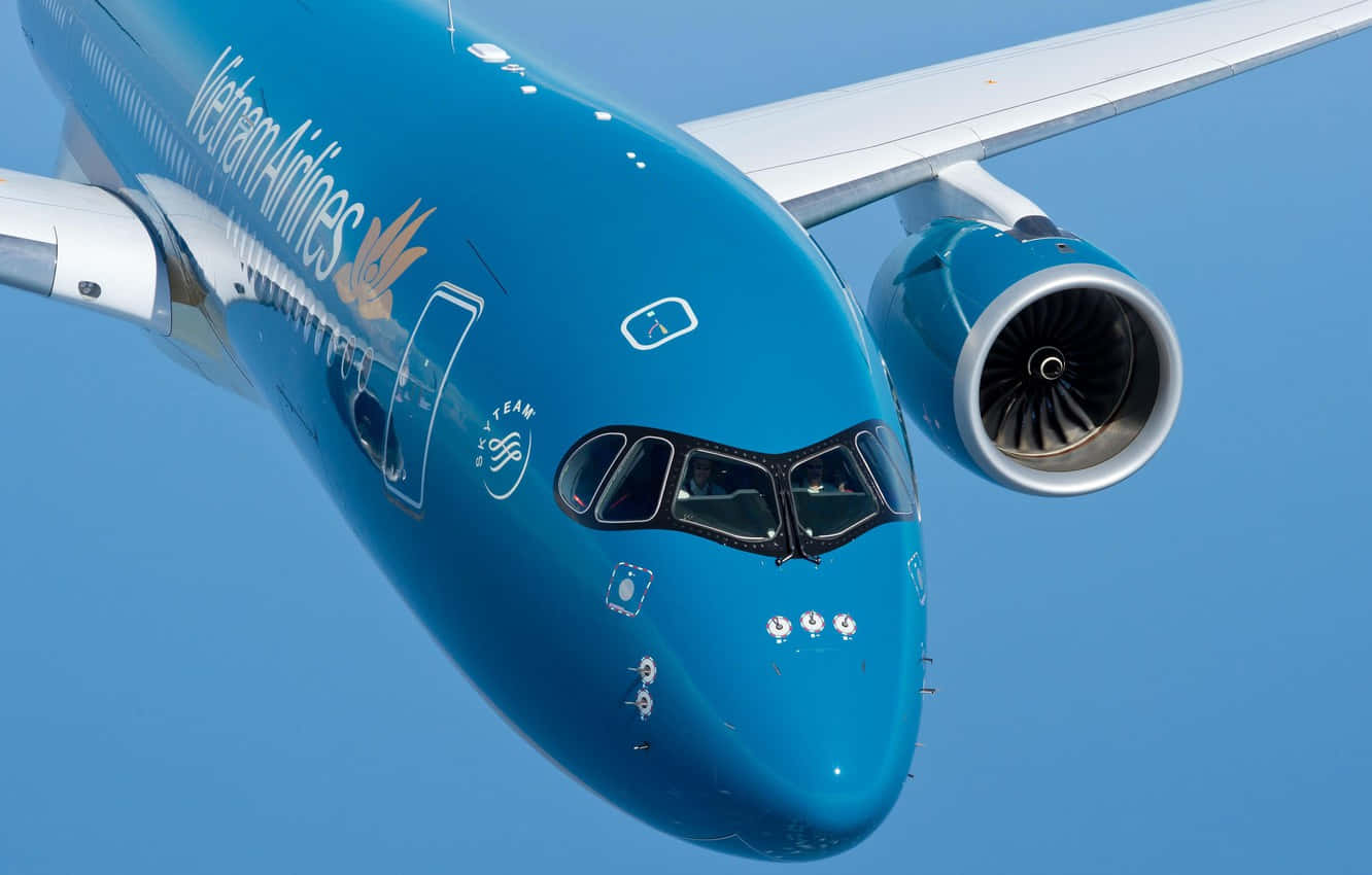 越南航空藍色飛機駕駛員 壁紙 — 越南航空飛機的藍色機身和引擎特寫，在晴朗的天空中翱翔。