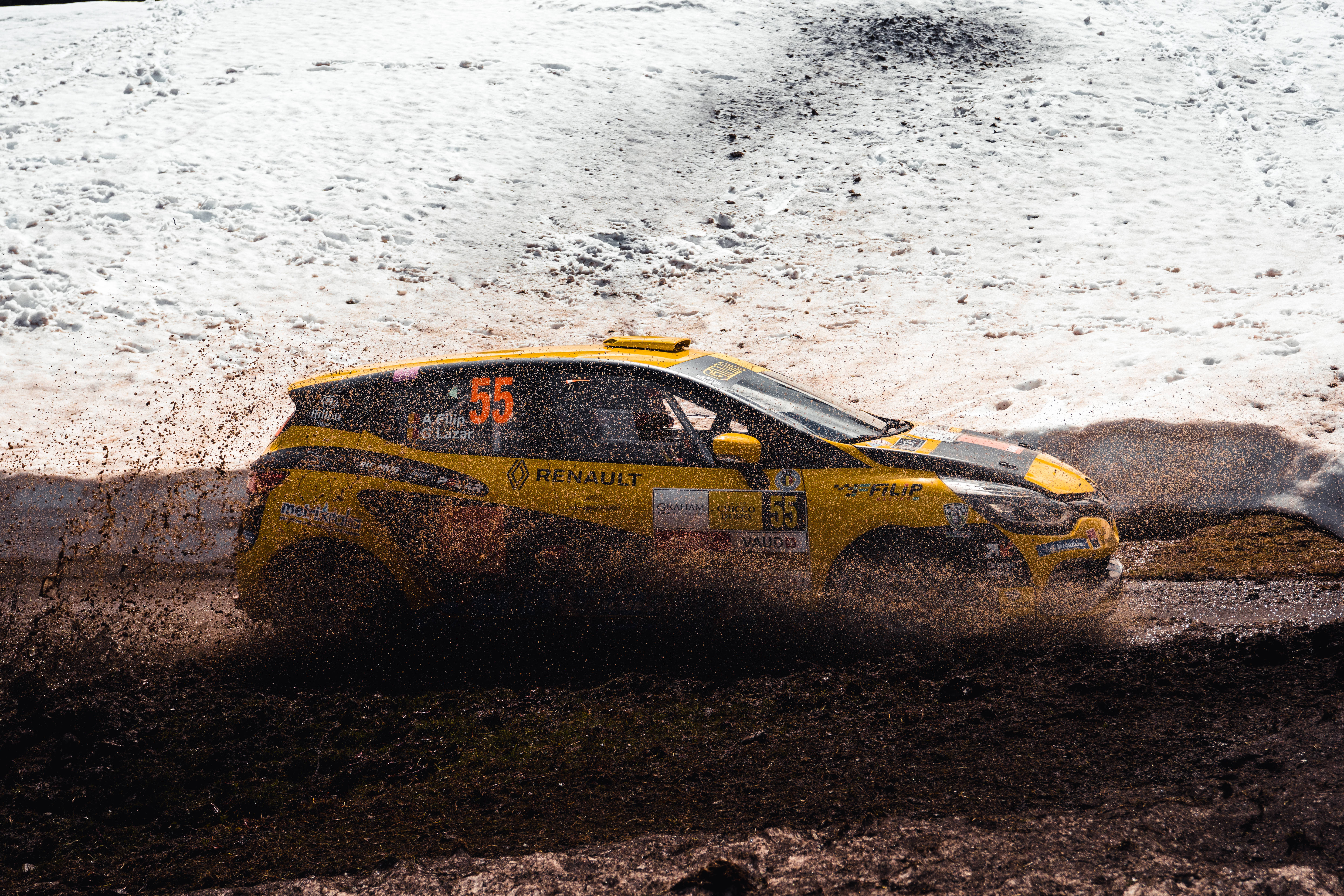 越野拉力賽車Renault Mégane R.S. 壁紙 — 一輛黃色拉力賽車（編號55）在雪地地形上疾馳，揚起泥濘和雪花，動感十足。