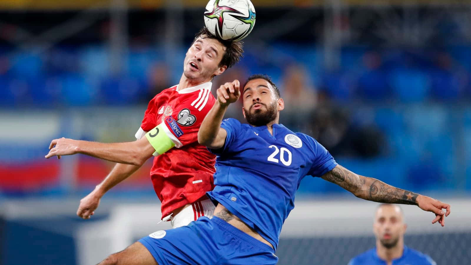 兩名足球員在比賽中跳起頂球。