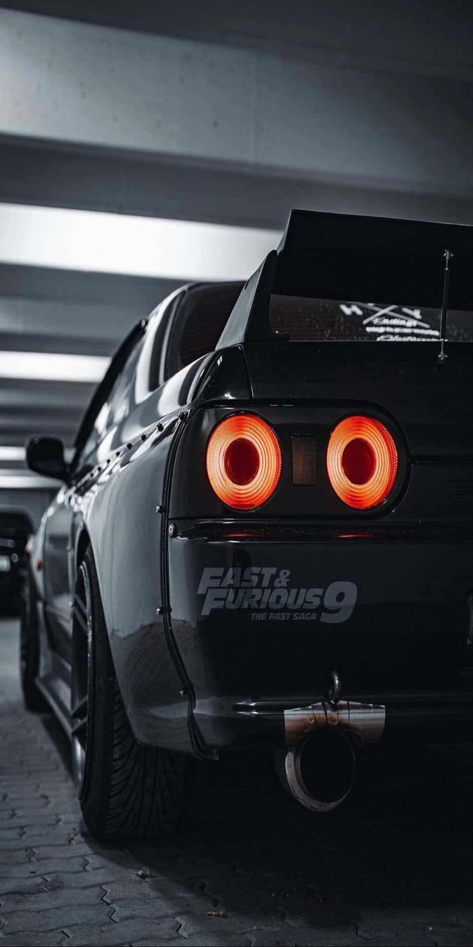 黑色日產Skyline R34在黑暗車庫中帶有發光的橙色尾燈。