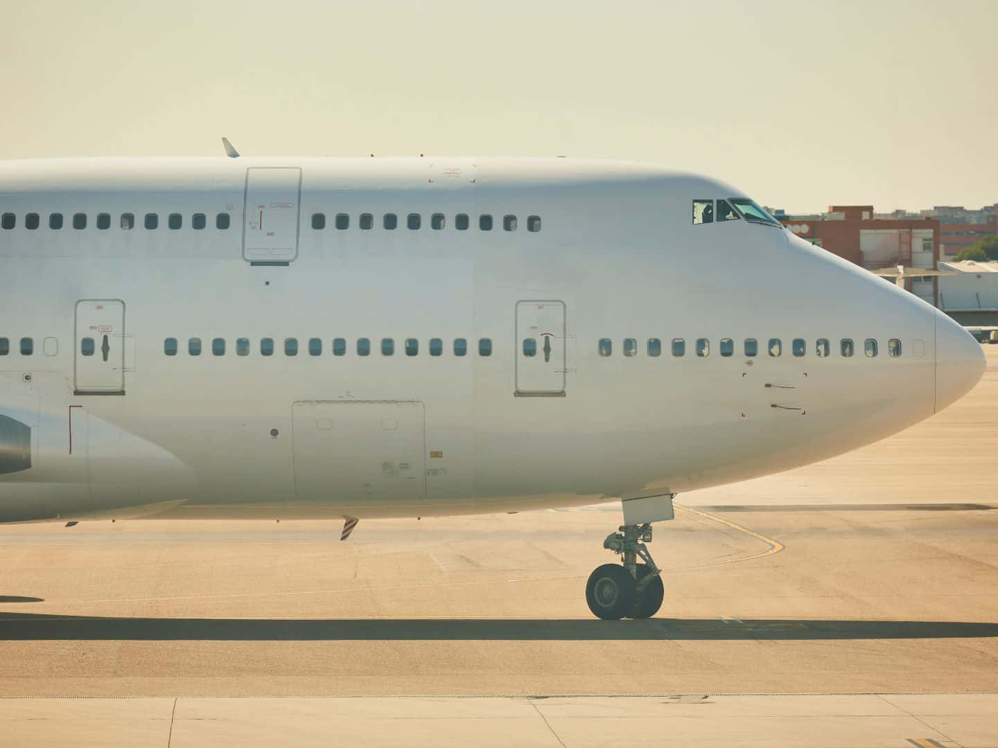 一架白色商用飛機在明亮陽光下停泊在機場停機坪上。