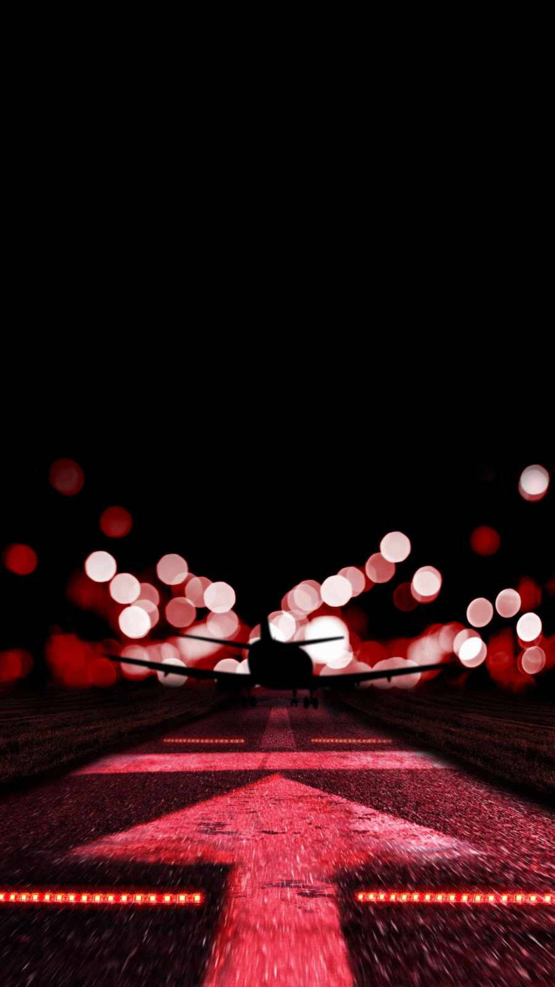 跑道上的粉紅箭頭 壁紙 — 夜間跑道上飛機的剪影，帶有發光的紅燈和散景效果。