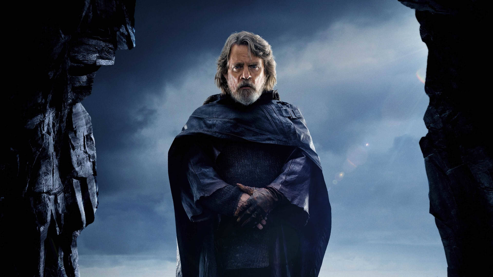 Luke Skywalker 身穿深色斗篷站在風暴天空下的岩石縫中