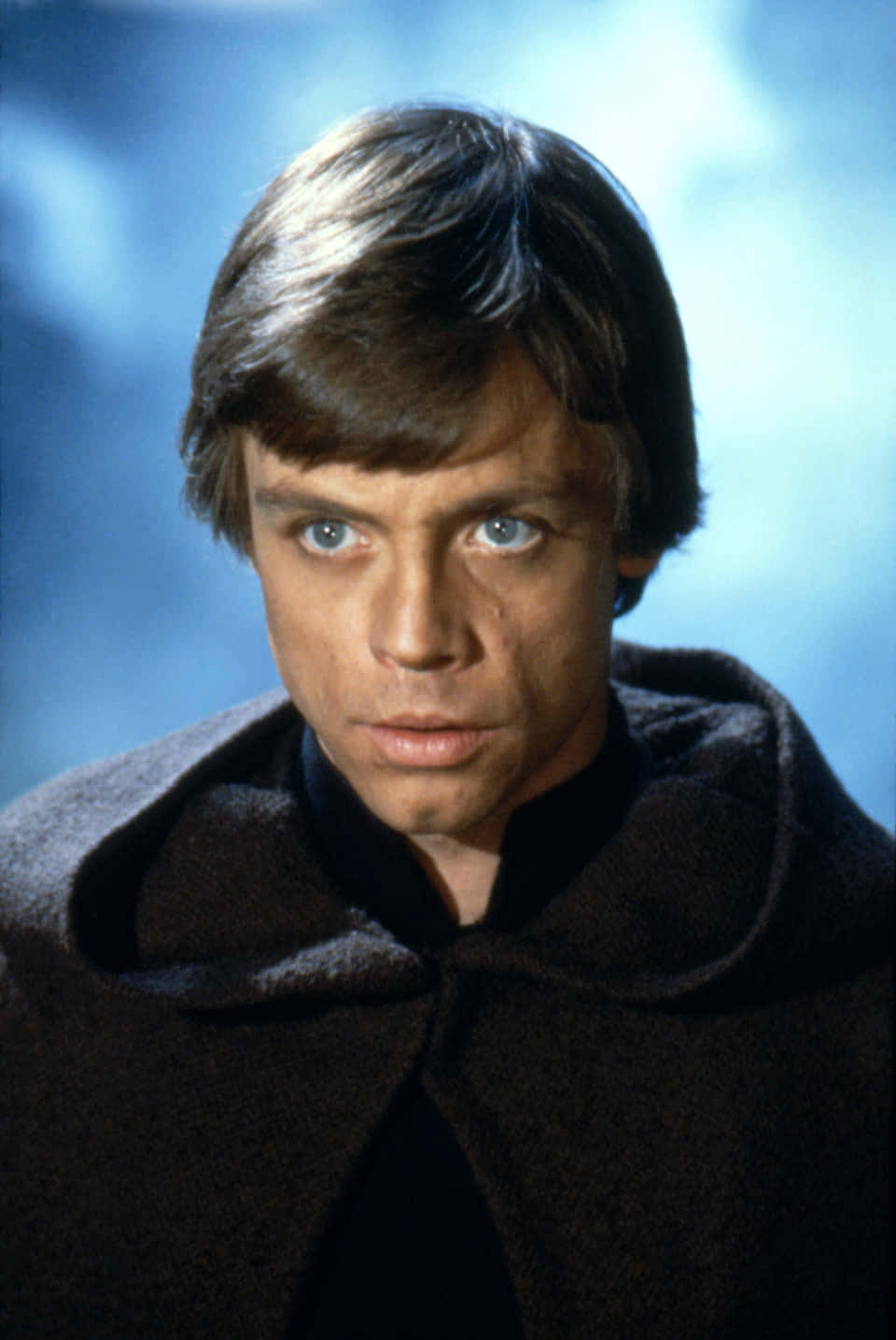 Return Of The Jedi 桌布 壁紙 — 路克·天行者身穿深色長袍，以柔和藍色雲朵背景的 close-up 肖像。