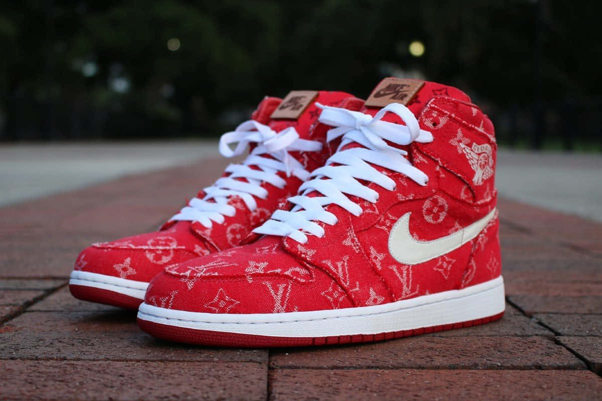 磚砌路面上的紅色 Louis Vuitton x Nike Air Jordan 1 運動鞋。