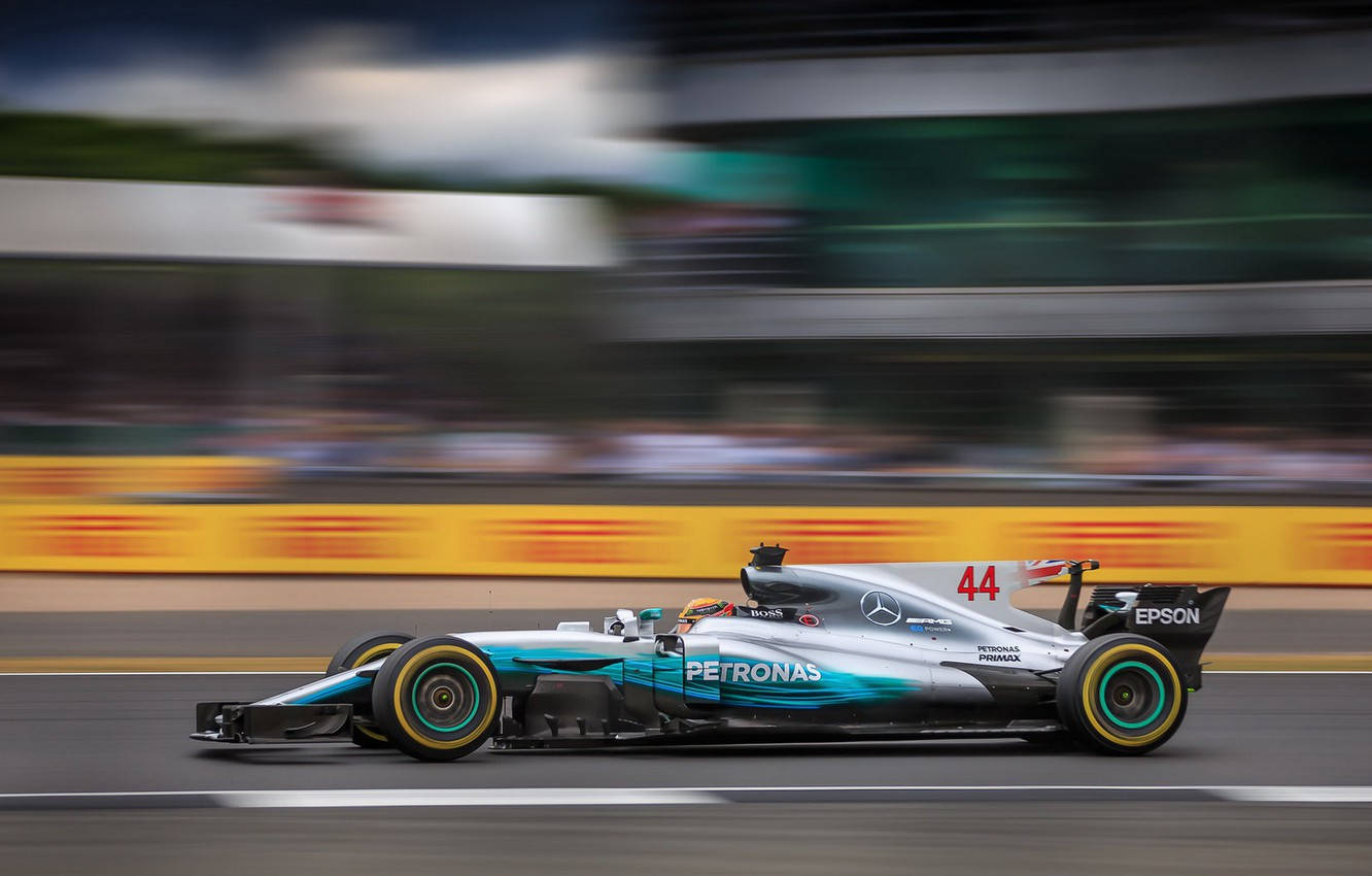 銀色和藍綠色的 Formula 1 賽車在模糊的背景中於賽道上高速行駛。