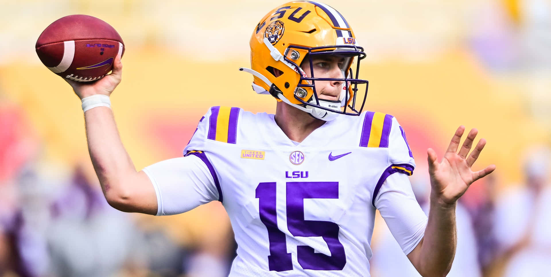 LSU 足球運動員身穿白色和紫色制服，在比賽中投擲足球。