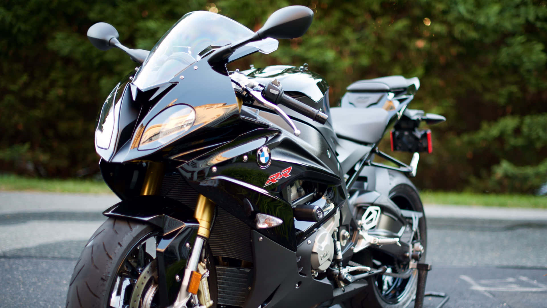 黑色BMW R1200RR運動電單車停泊在瀝青路上，背景有綠色樹木。