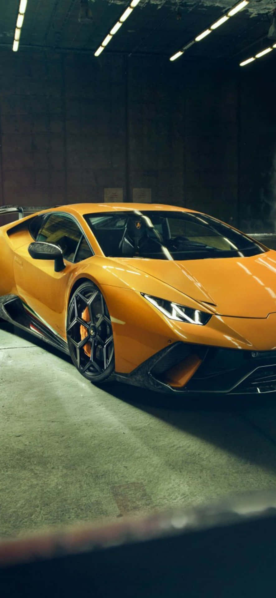 螢光燈下的混凝土車庫中的橙色林寶堅尼 Huracán。