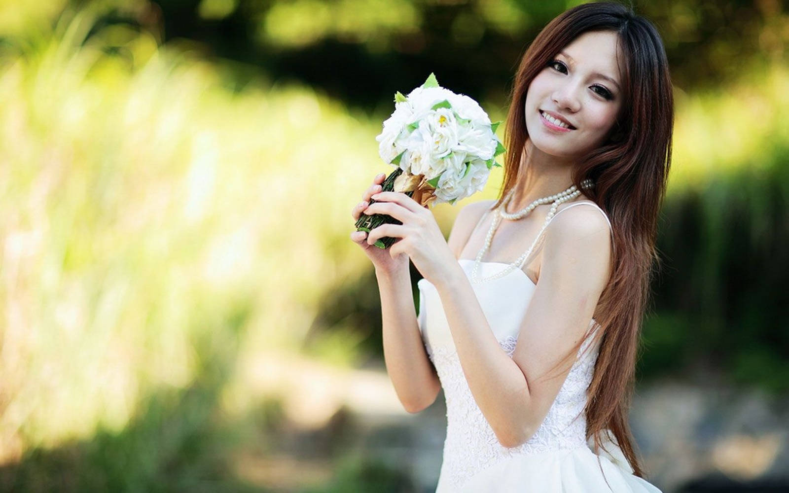 白裙女士在戶外陽光下手持白色花束。