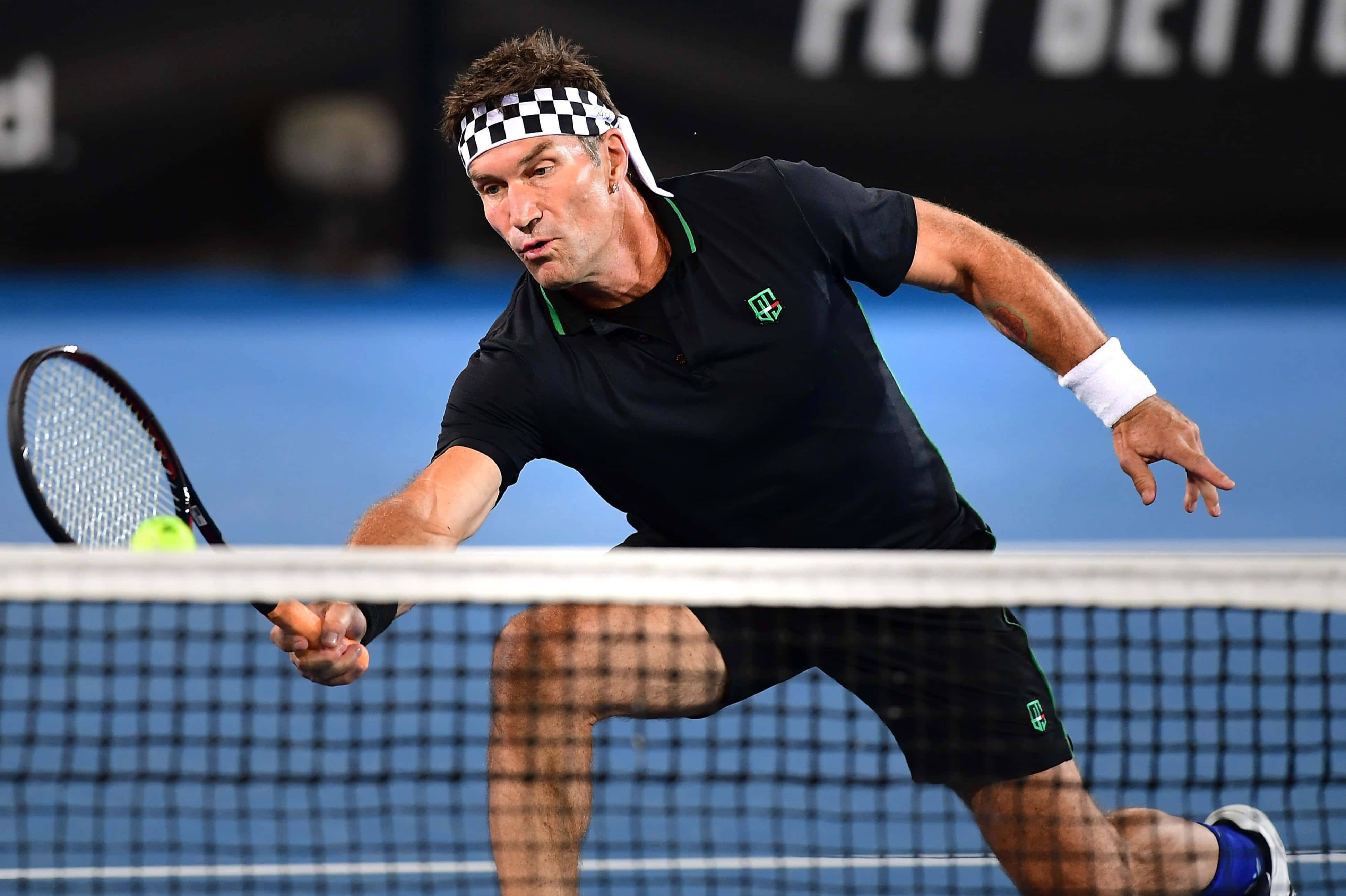 身穿全黑戰袍的澳洲職業網球選手 Pat Cash 壁紙 — 一名男性網球選手在職業比賽中，帶著強烈的專注力向前撲身，在網前擊出正手拍。