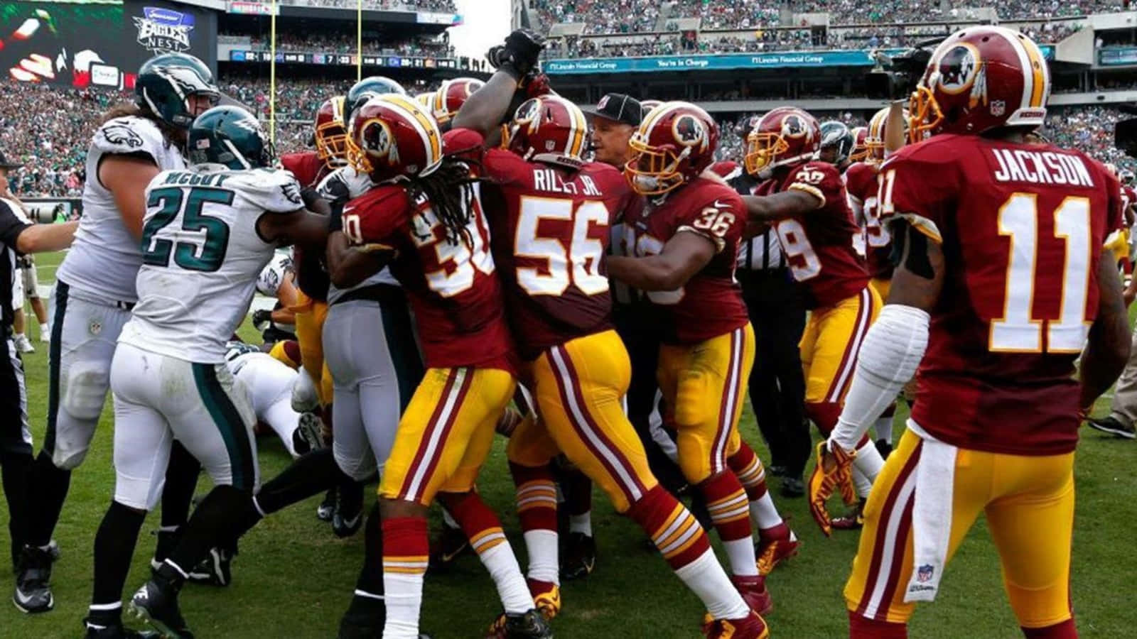 Washington Football 桌布 壁紙 — 身穿栗色和金色球衣的足球員在綠色球場上慶祝達陣，背景是座無虛席的體育場。