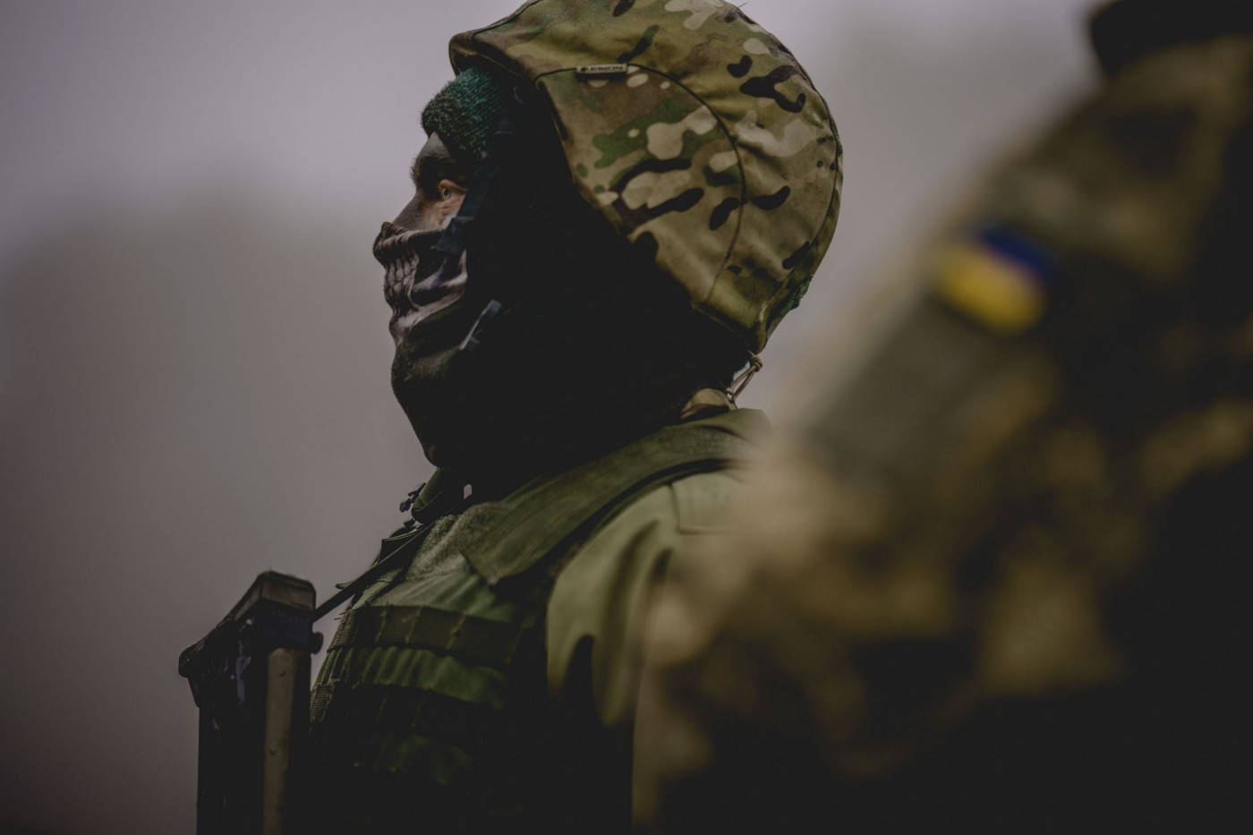 身穿迷彩服和骷髏面罩的士兵側面站立