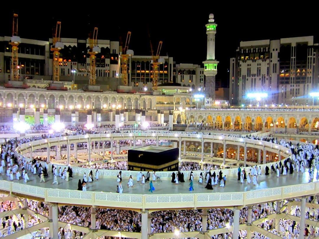 Makkah 桌布 壁紙 — 身穿白衣的朝聖者人群在麥加夜晚的明亮燈光下繞行卡巴天房。