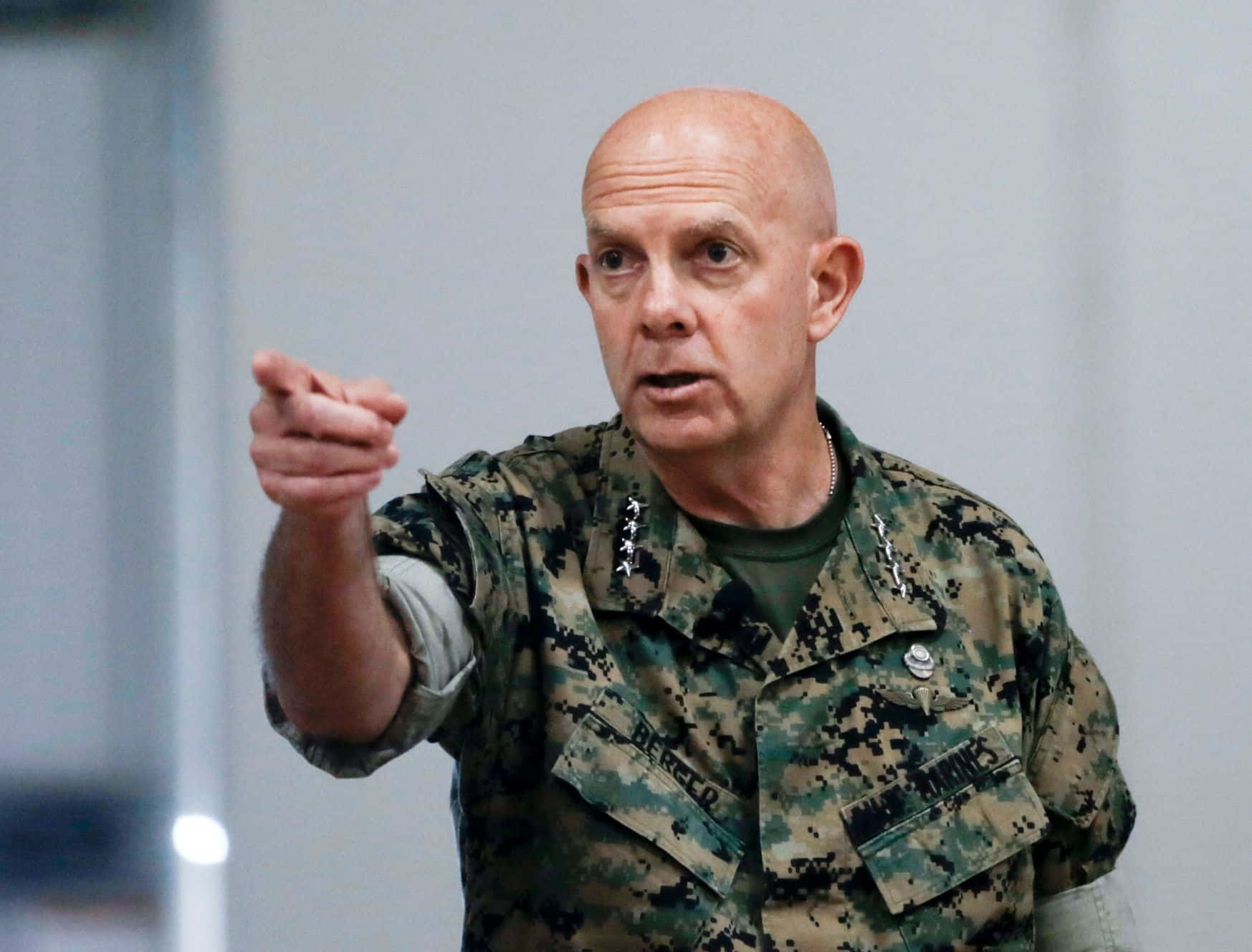 身穿迷彩服的軍官在室內向前指。