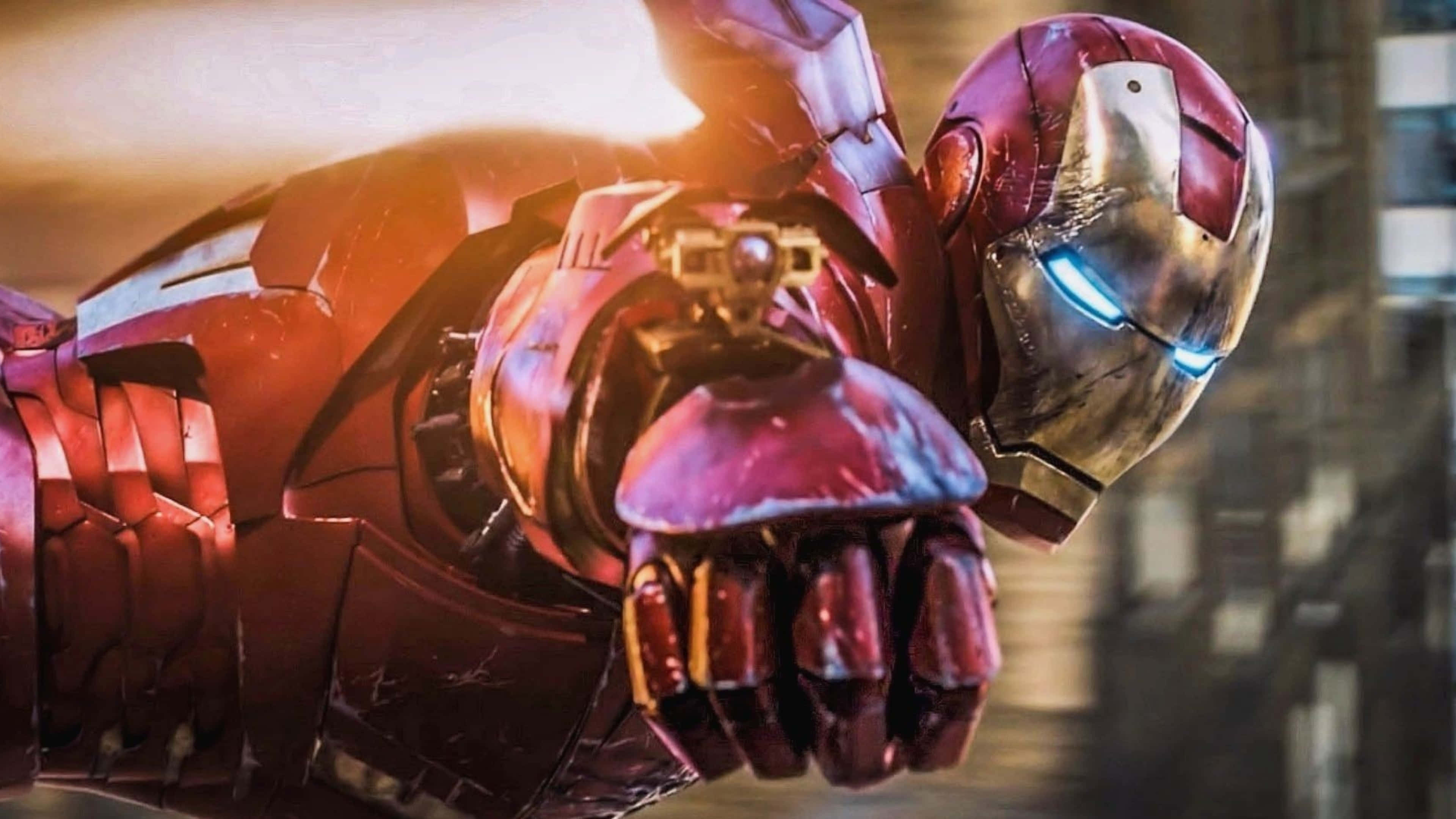 4K Marvel 壁紙 桌布 壁紙 — 身穿紅色和金色盔甲的鐵甲奇俠，在模糊的城市景觀背景下，伸出他的手，眼睛發出藍光。