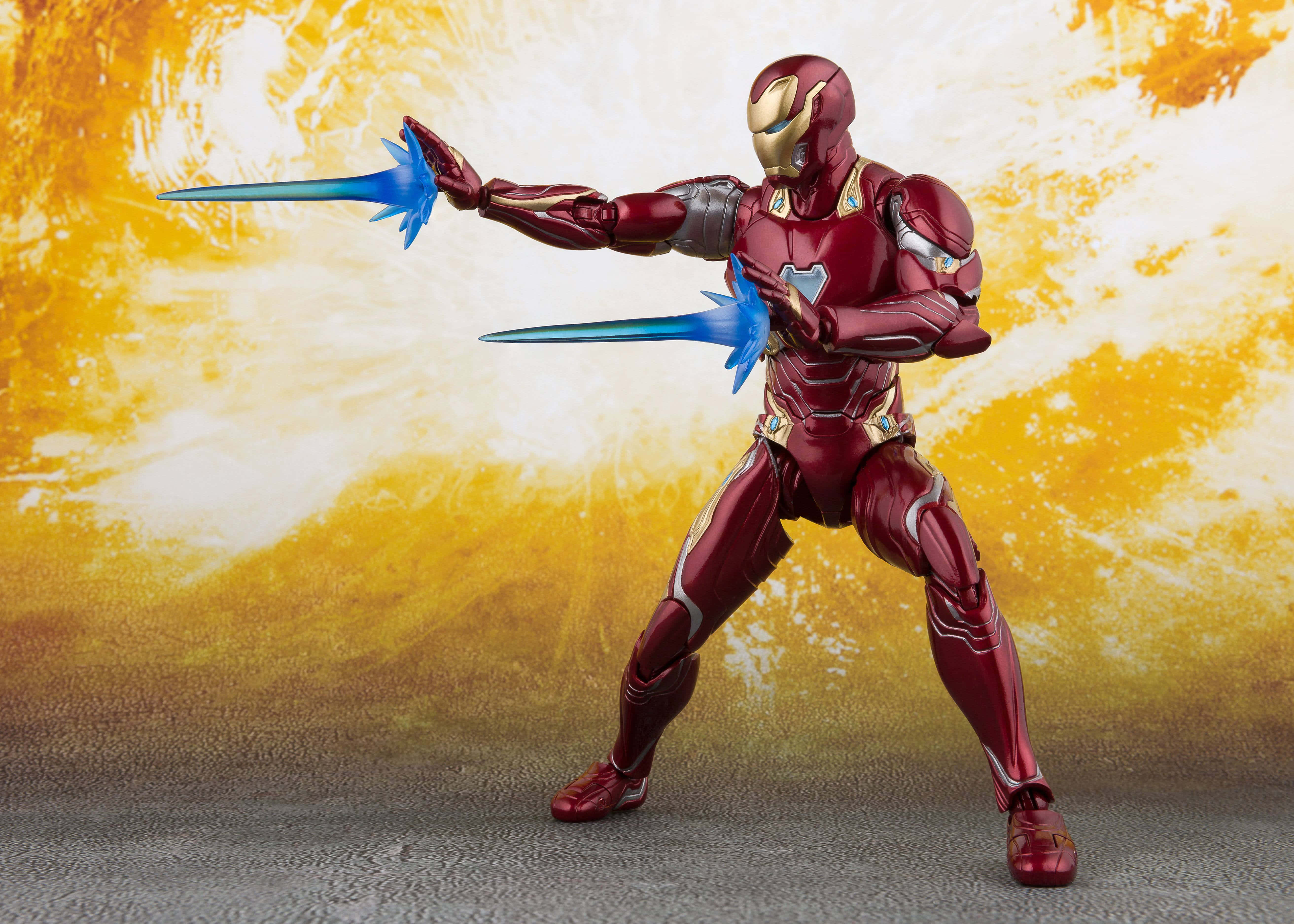 Iron Man Action Figures 桌布 壁紙 — 身穿紅色和金色盔甲的鐵甲奇俠動作人偶，在熾熱的黃色和白色背景下發射藍色斥力光束。