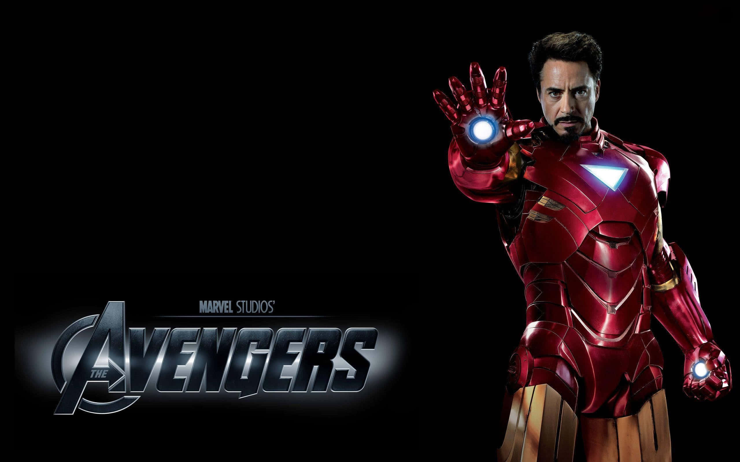 Iron Man Movies 桌布 壁紙 — 身穿紅色和金色裝甲的鐵甲奇俠在帶有復仇者聯盟標誌的黑色背景前伸出發光的斥力炮手。