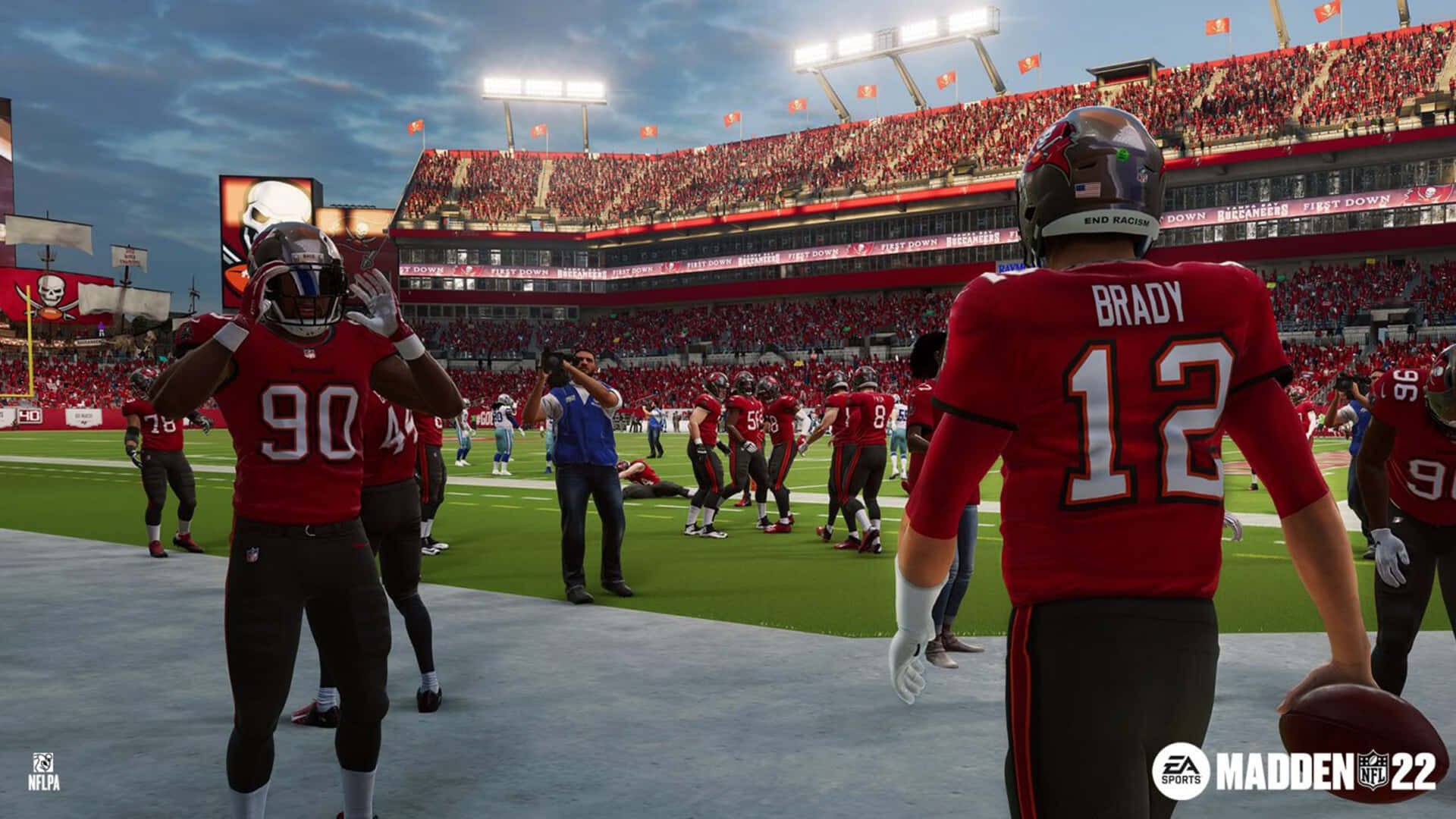 Madden NFL 22 桌布 壁紙 — 身穿紅色球衣的足球運動員在夜間燈光下聚集在球場上，看台座無虛席。