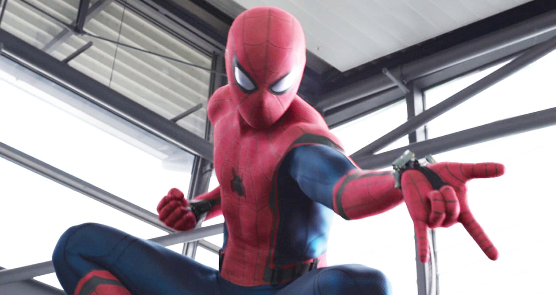Spider-man Web Shooter 桌布 壁紙 — 身穿紅藍戰衣的蜘蛛俠在明亮的日光下蹲在金屬橫樑上。