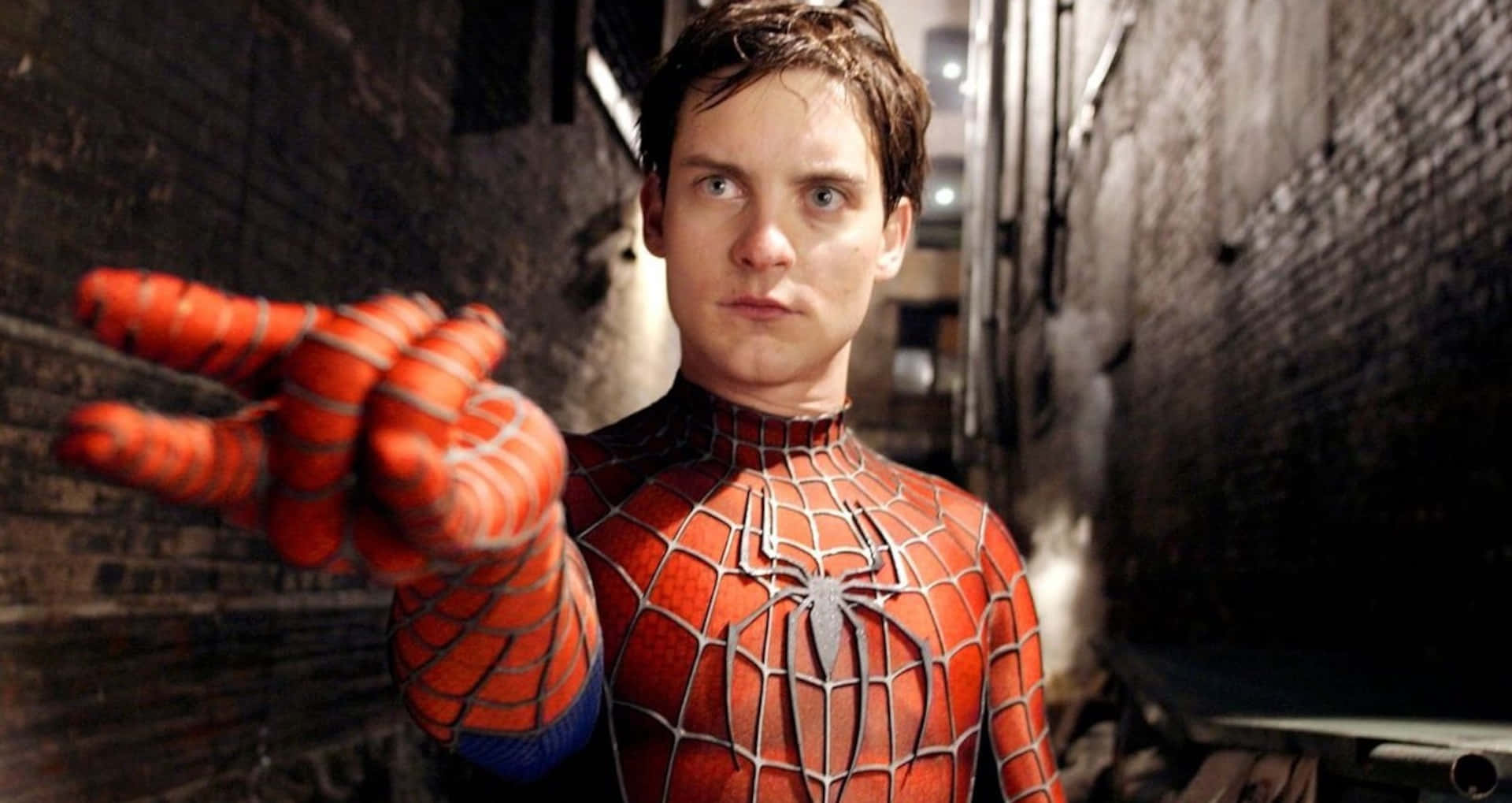Spider-man Web Shooter 桌布 壁紙 — 身穿紅藍戰衣的蜘蛛俠站在骯髒的小巷中，專注地向前伸出手。