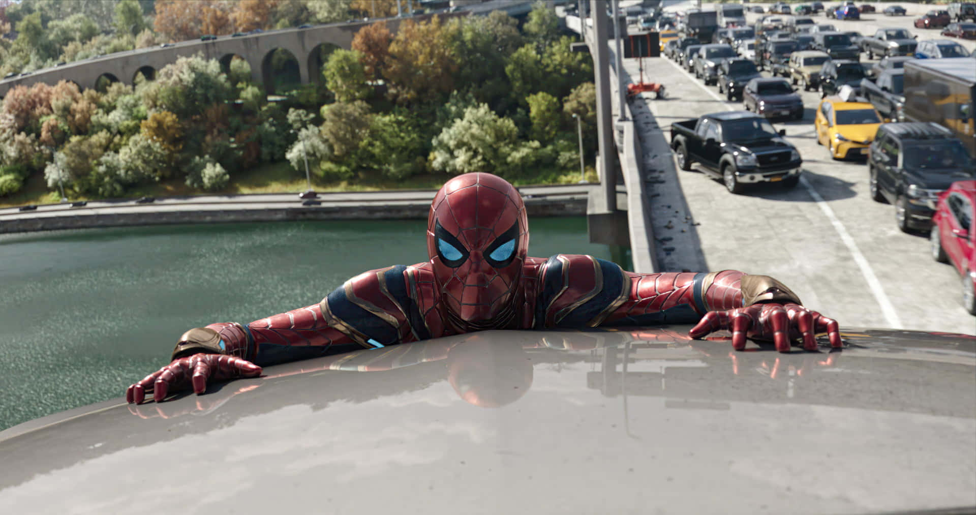 Spider Man No Way Home 桌布 壁紙 — 身穿紅金戰甲的蜘蛛俠靠喺高速公路天橋上，俯瞰車流同綠化地帶。