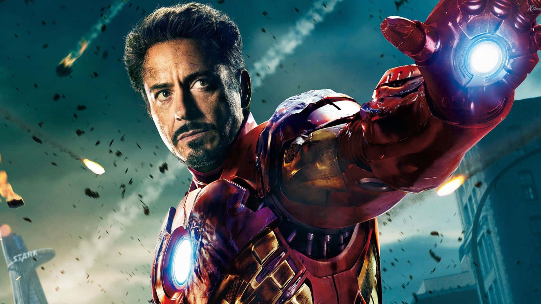 Superhero Movies 桌布 壁紙 — 身穿紅金裝甲的鐵甲奇俠在都市景觀中，於墜落的碎片和燃燒的彈體之間發射斥力光束。