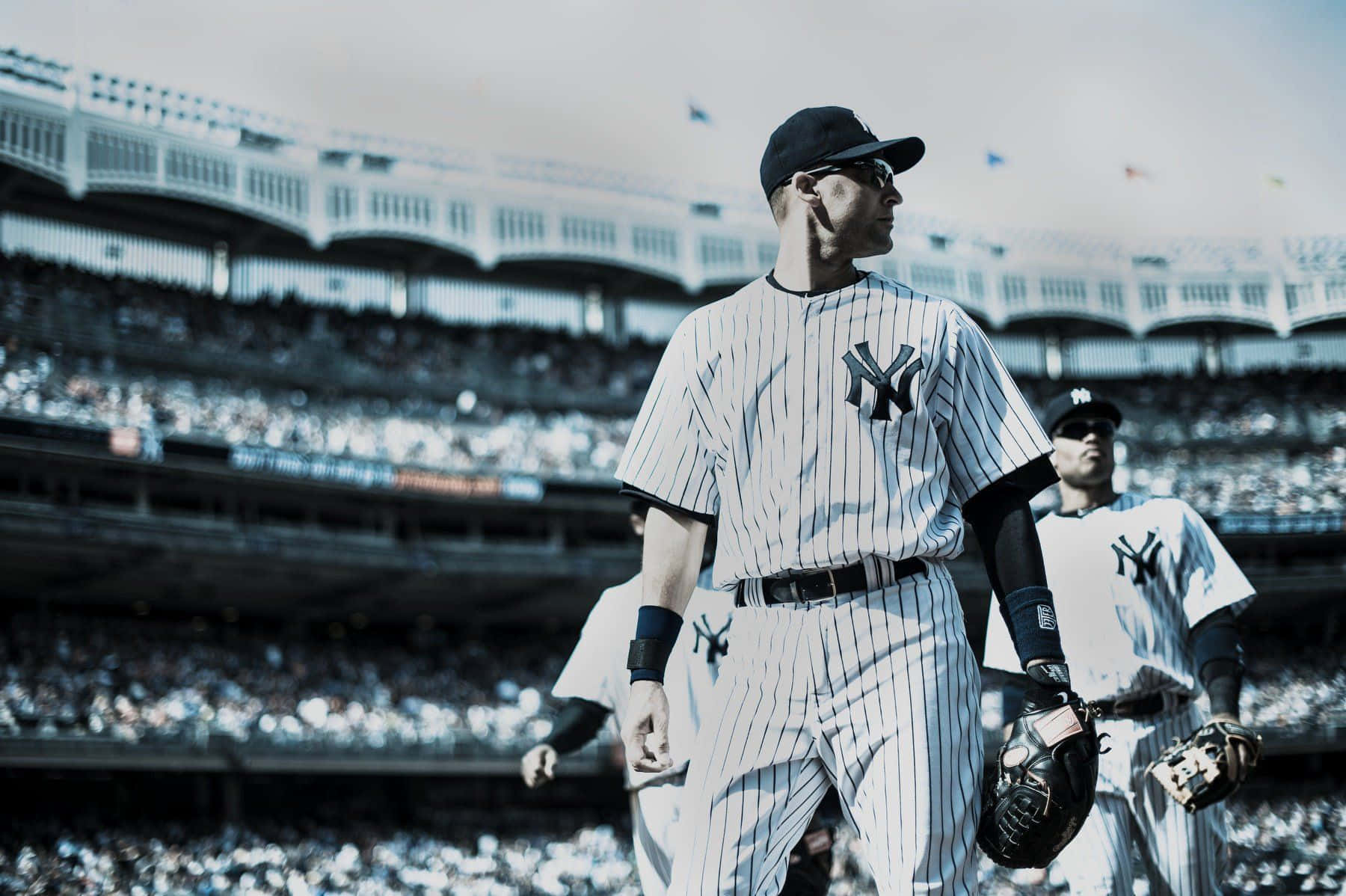 MLB Baseball League 桌布 壁紙 — 身穿細條紋球衣的棒球運動員在陽光普照、坐滿觀眾的球場上走過。
