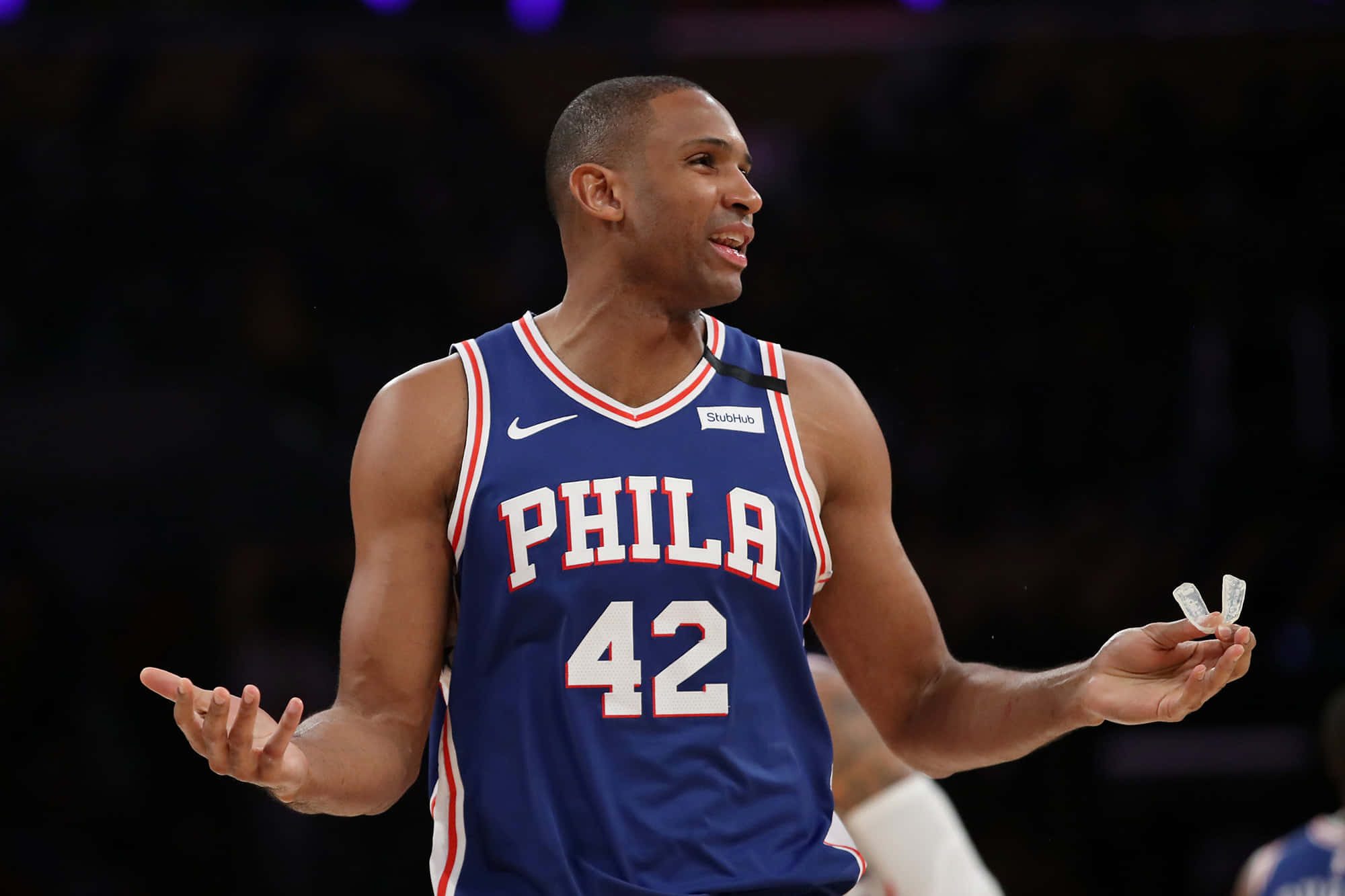 Al Horford 桌布 壁紙 — 身穿藍色Phila球衣42號的籃球運動員在場館燈光下比賽時攤開雙手聳肩。