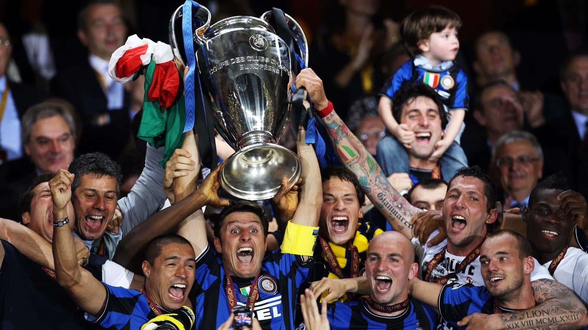 Inter Milan 桌布 壁紙 — 身穿藍黑間條球衣的足球運動員在體育場人群中歡欣鼓舞地將閃亮的銀色獎盃高舉過頭頂。
