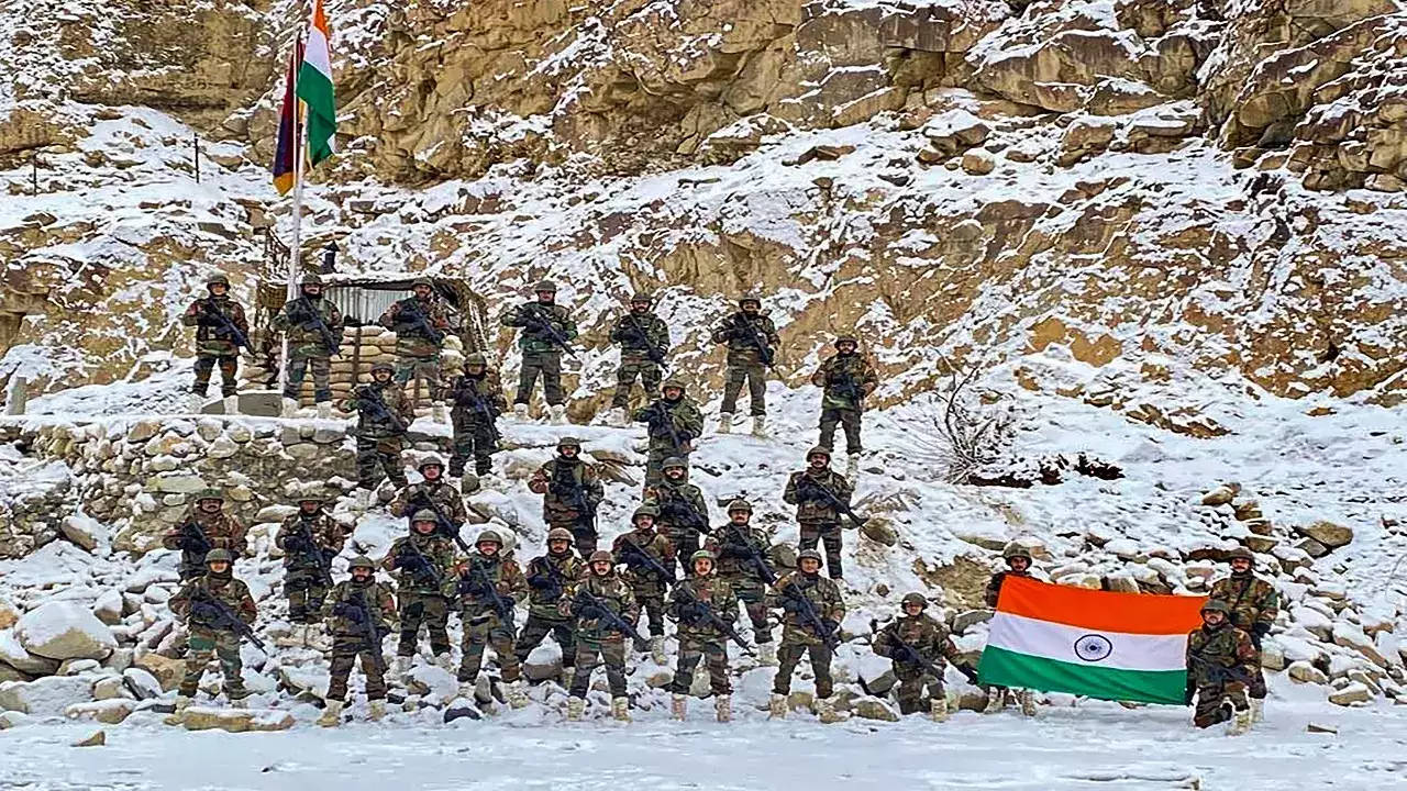 Indian Army 桌布 壁紙 — 身穿迷彩服的印度士兵在白雪覆蓋的岩石山坡上列隊，手持國旗。