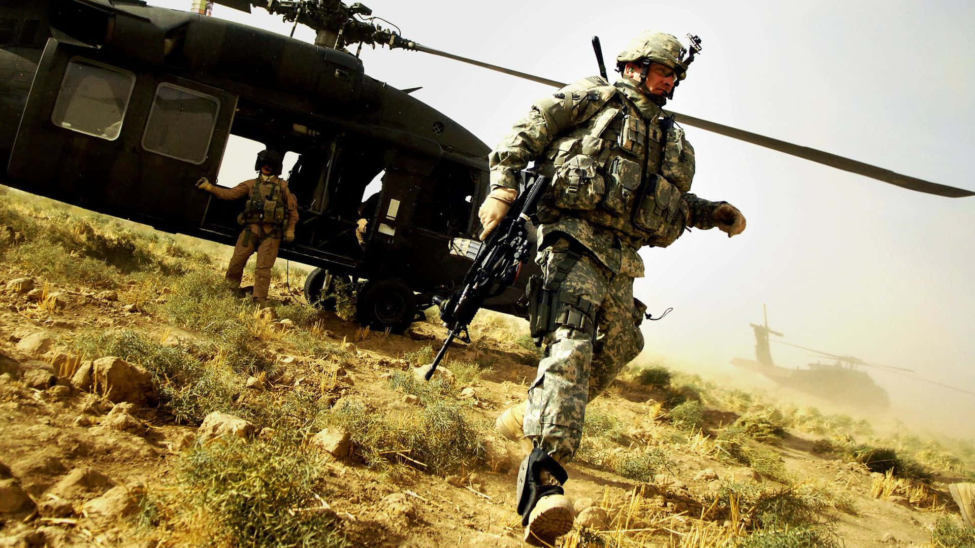 Army 桌布 壁紙 — 身穿迷彩裝備的士兵在塵土飛揚的地形上衝刺，而一架黑色直升機在沙漠景觀中盤旋在附近。