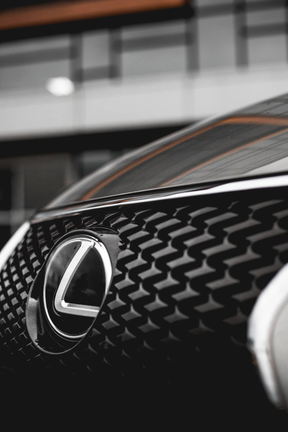 黑色Lexus汽車格柵近距離特寫，帶有鍍鉻標誌和橙色條紋。