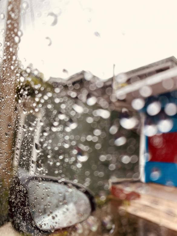 窗上的雨滴遮擋了外面的汽車和色彩繽紛的建築物。