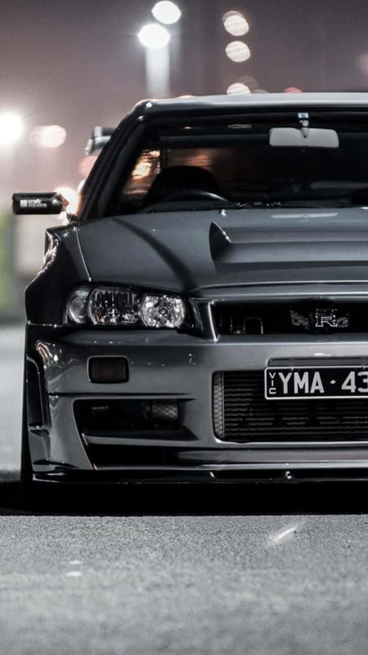 黑色日產Skyline R34在夜晚停泊在城市的街燈下。